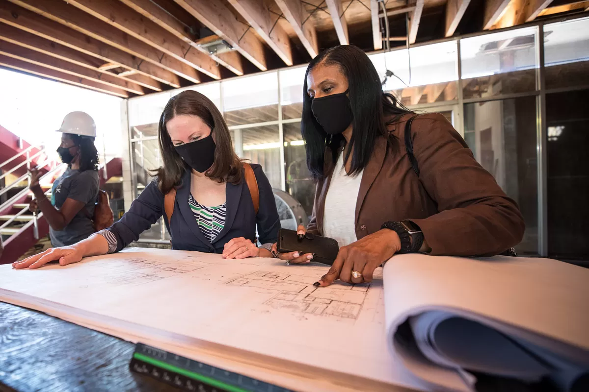 two staff members looking at building plans